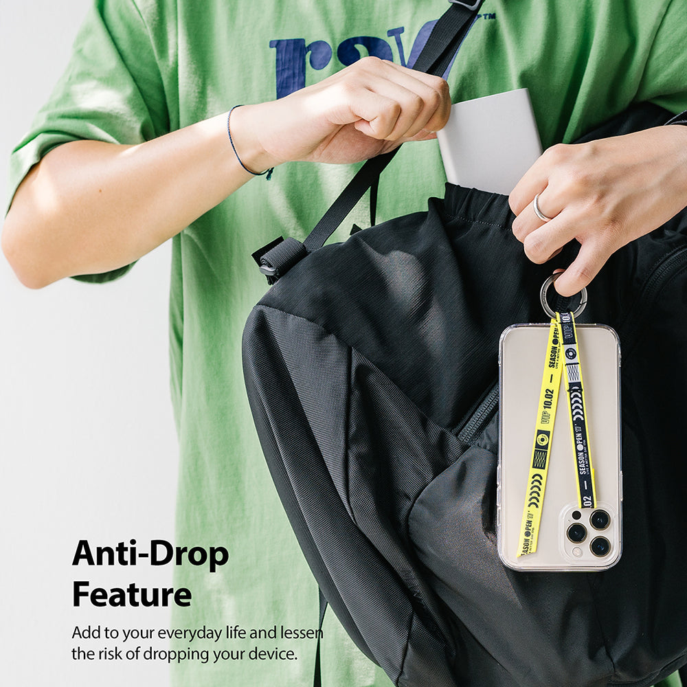 Ring Band Strap - A person in a green shirt attaches a yellow phone strap to a black backpack.