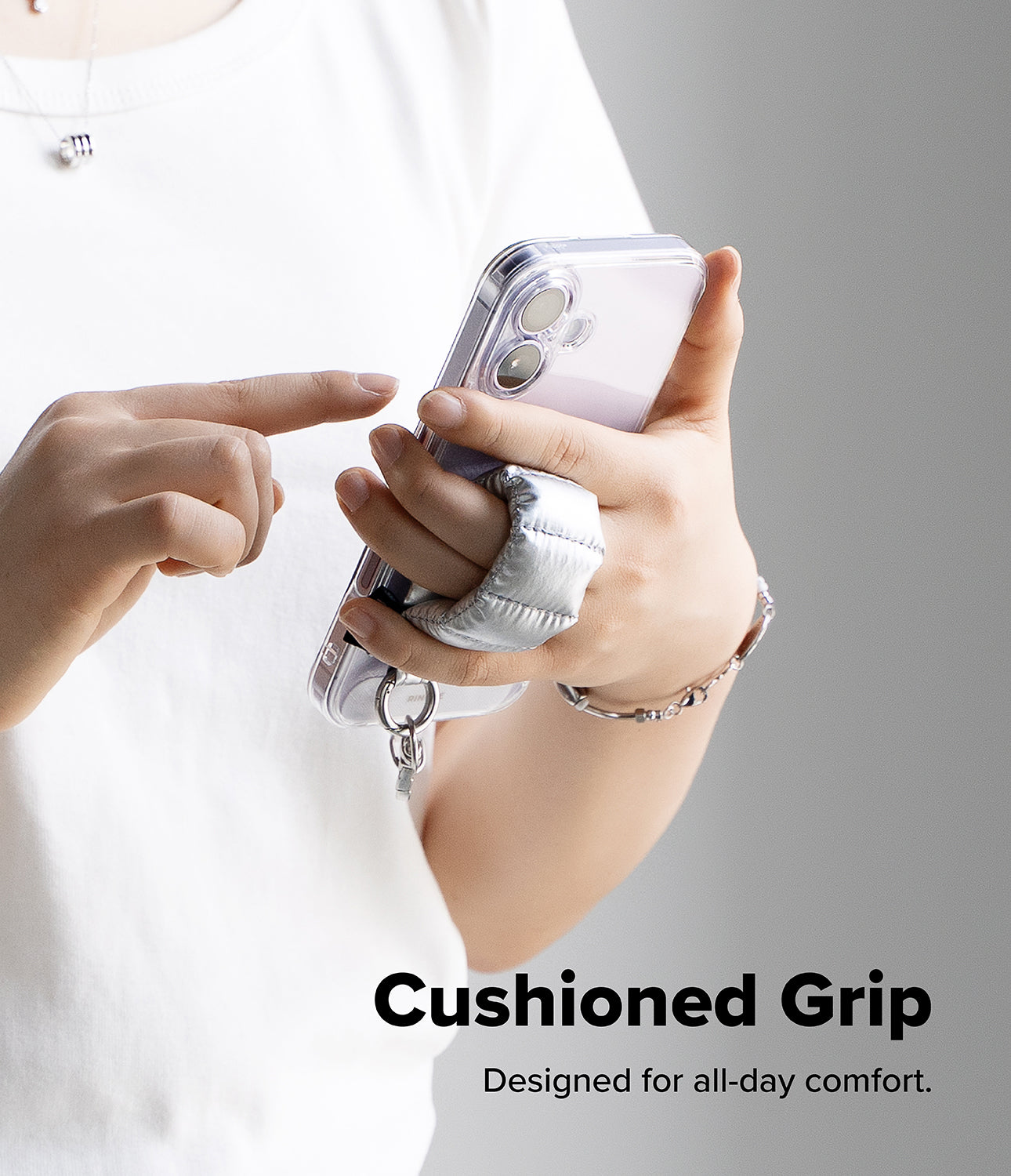 Holder Link Puffer | Finger - A person holding a phone with a sliver, quilted, cushioned finger strap for a secure grip.