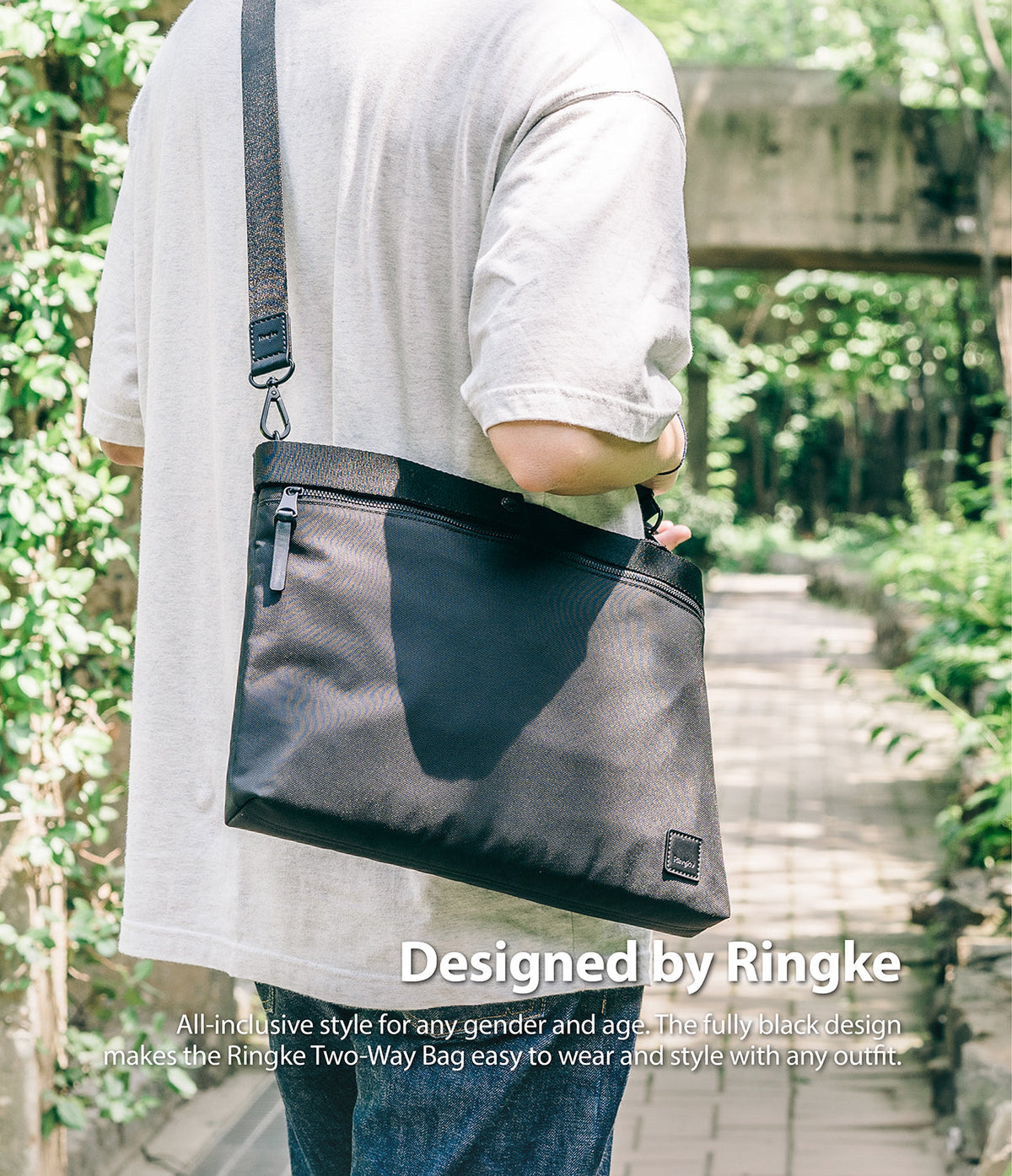 2-Way Bag - A person wearing a black crossbody bag with a textured strap against a blurred outdoor park background.