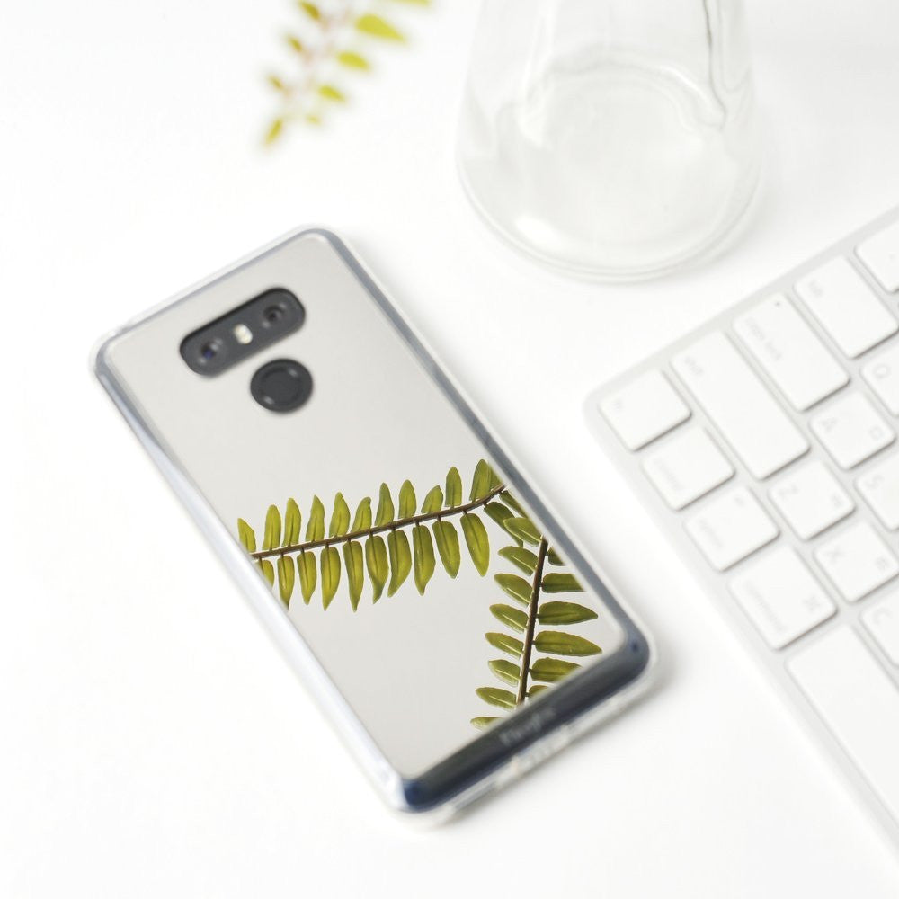 LG G6 Case | Mirror - Reflective phone case featuring a green fern leaf design, placed on a white desk next to a keyboard.