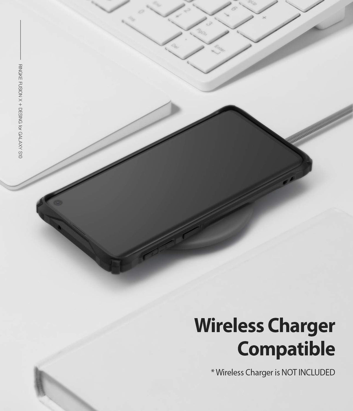 Galaxy S10 Case | Fusion-X Design - Black phone case on a wireless charging pad next to a white keyboard and notebook.