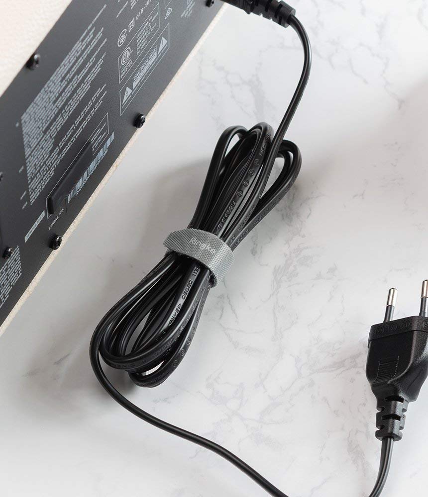Magic Cable Tie - A grey Ringke velcro cable tie securing a coiled black power cord against a white marble surface.