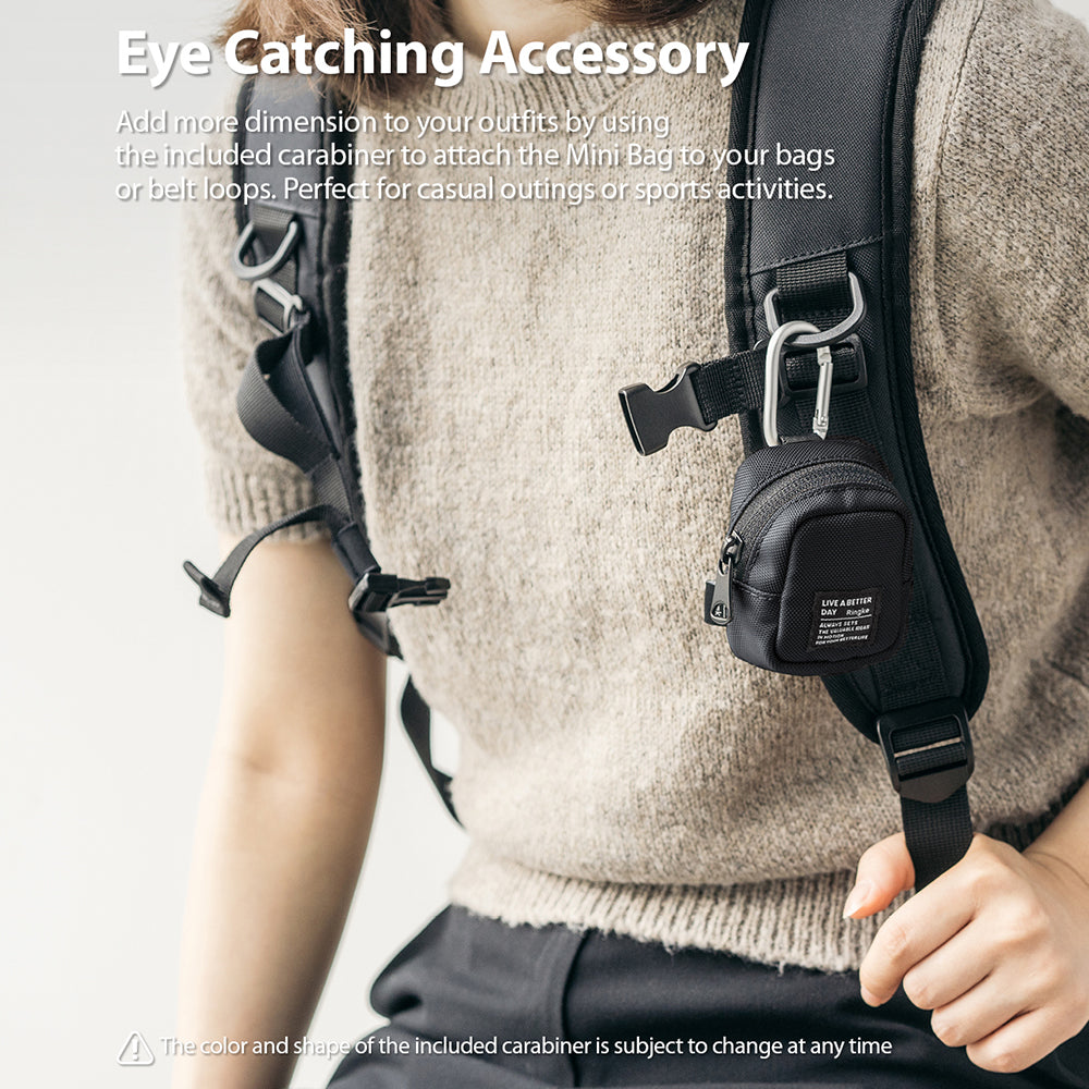 Mini Pouch | Block - A small black pouch attached to a backpack strap with a silver carabiner, worn by a person in a sweater.