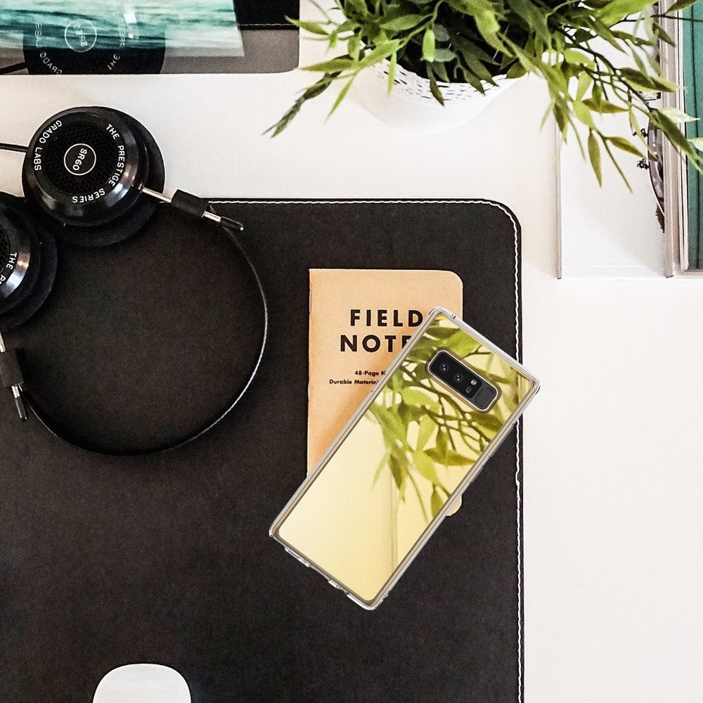 Galaxy Note 8 Case | Mirror - Reflective phone case on a desk with a notebook, headphones, and a plant.