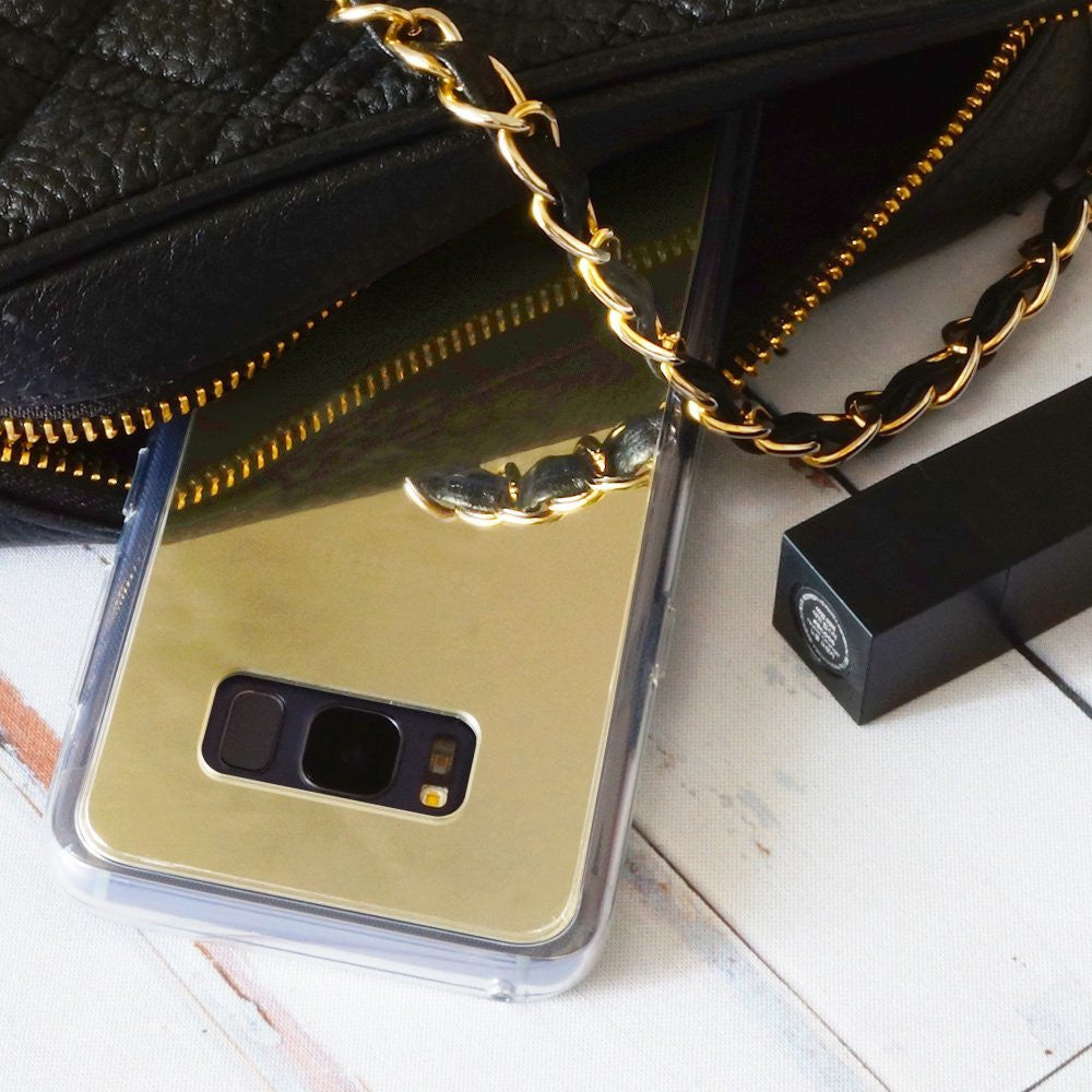 Galaxy S8 Case | Mirror - Gold reflective phone case next to a black quilted purse with a gold chain strap and lipstick.