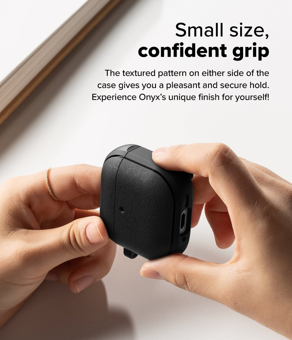AirPods 5 / 4 Case | Onyx Magnetic - Hands holding a black textured AirPods 4 case with side grip patterns on a white surface.