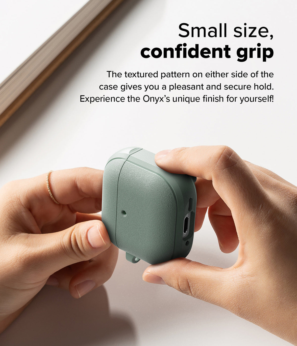AirPods 5 / 4 Case | Onyx Magnetic - Hands holding a sage green textured AirPods 4 case with side grip detailing.
