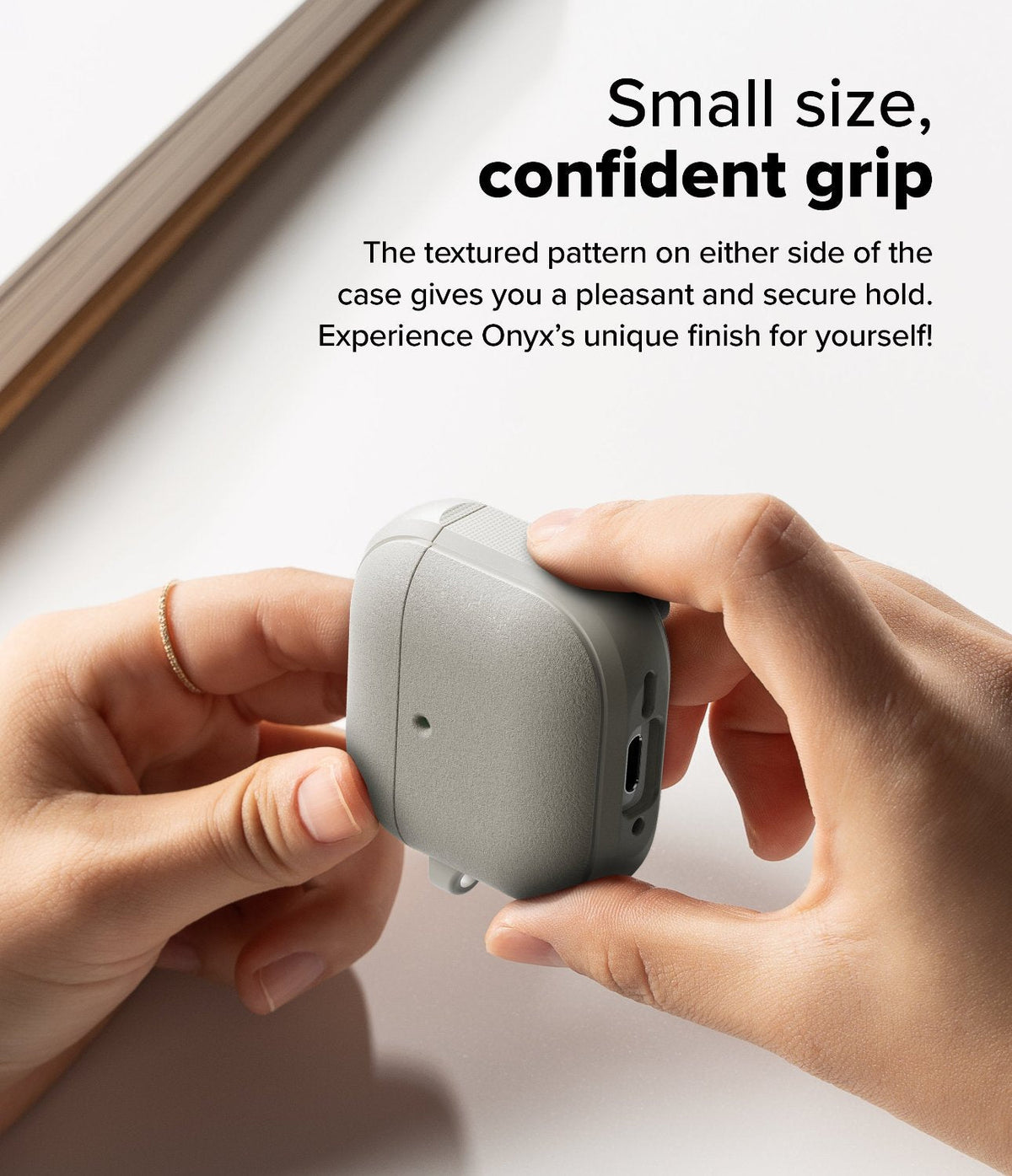 AirPods 5 / 4 Case | Onyx Magnetic - Hands holding a grey textured AirPods 4 case with side grip patterns on a white surface.