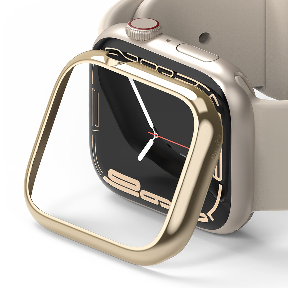 Apple Watch 9 / 8 / 7 (41mm) | Bezel Styling - Gold adhesive bezel frame hovering above a beige Apple Watch.