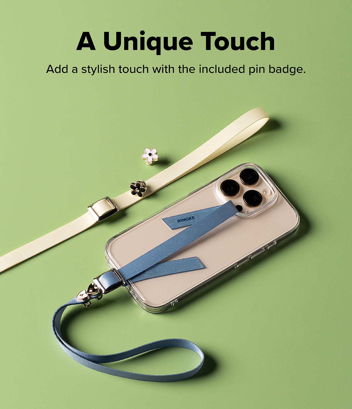 Band Buckle Rectangle Type Strap - A blue phone strap attached to a clear phone case, with a cream strap and flower pins nearby.