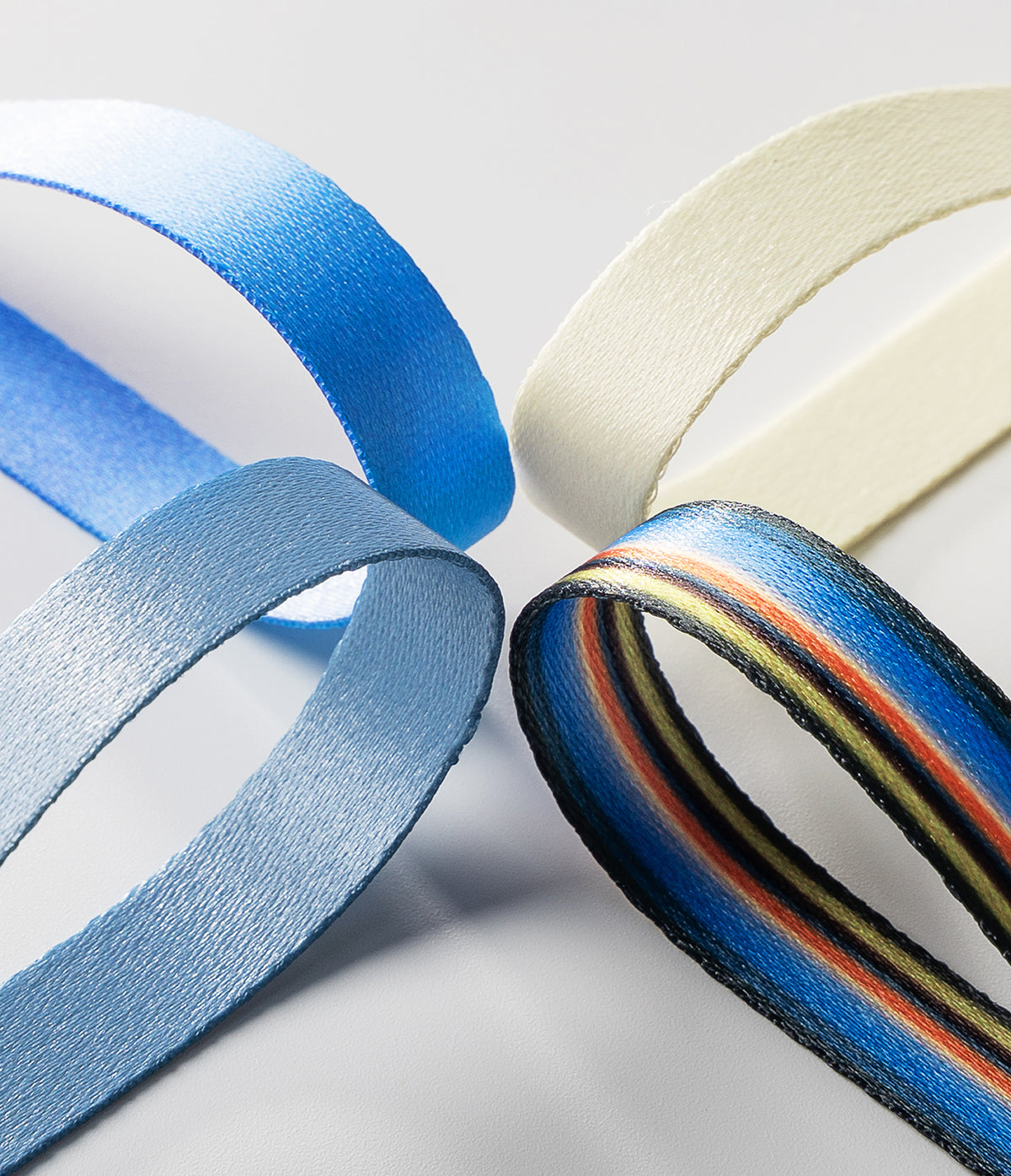 Band Strap - Four fabric straps in blue, light blue, cream, and multicolored stripes arranged in a circular pattern.