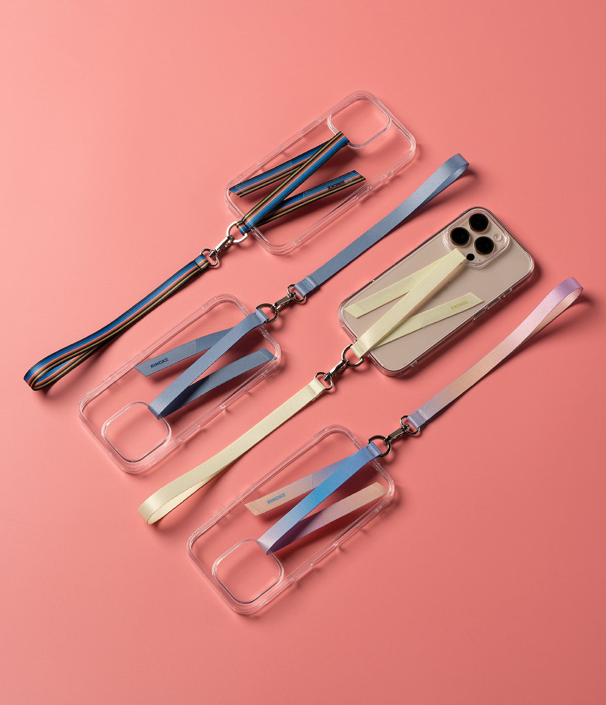 Band D Ring Hand Hook Strap - Four clear phone cases with colorful fabric wrist straps and metal D-ring hooks on a pink background.