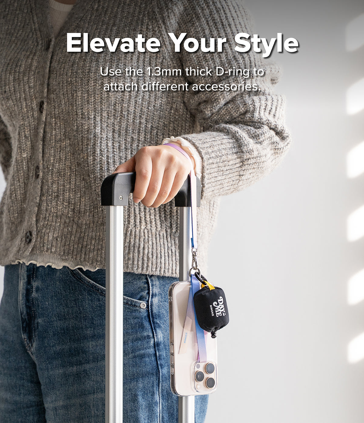 Band D Ring Hand Hook Strap - A person holding a suitcase handle with a phone and small pouch attached via a D-ring strap.
