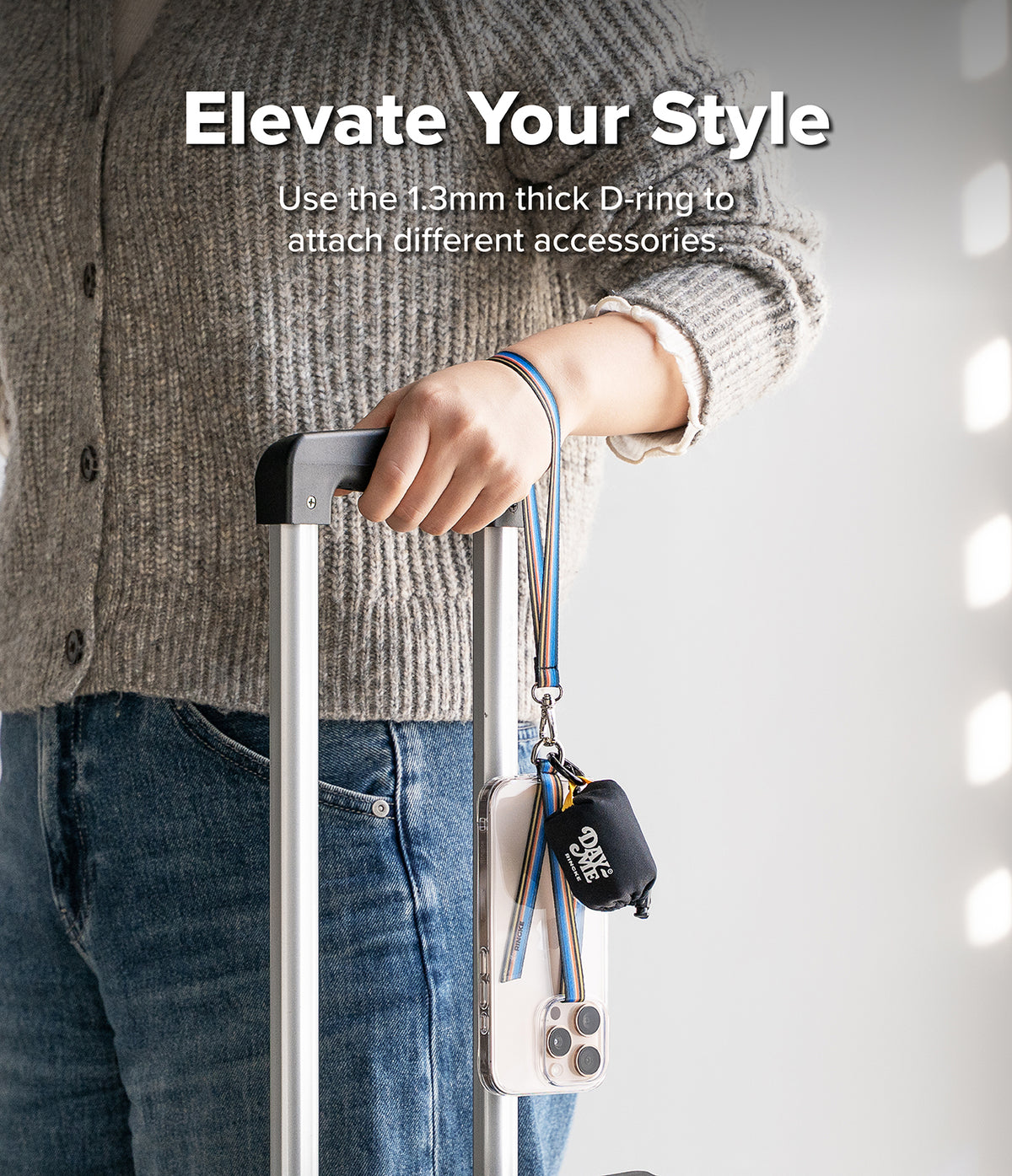 Band D Ring Hand Hook Strap - A person holding a suitcase handle with a colorful wrist strap attached to a phone and pouch.