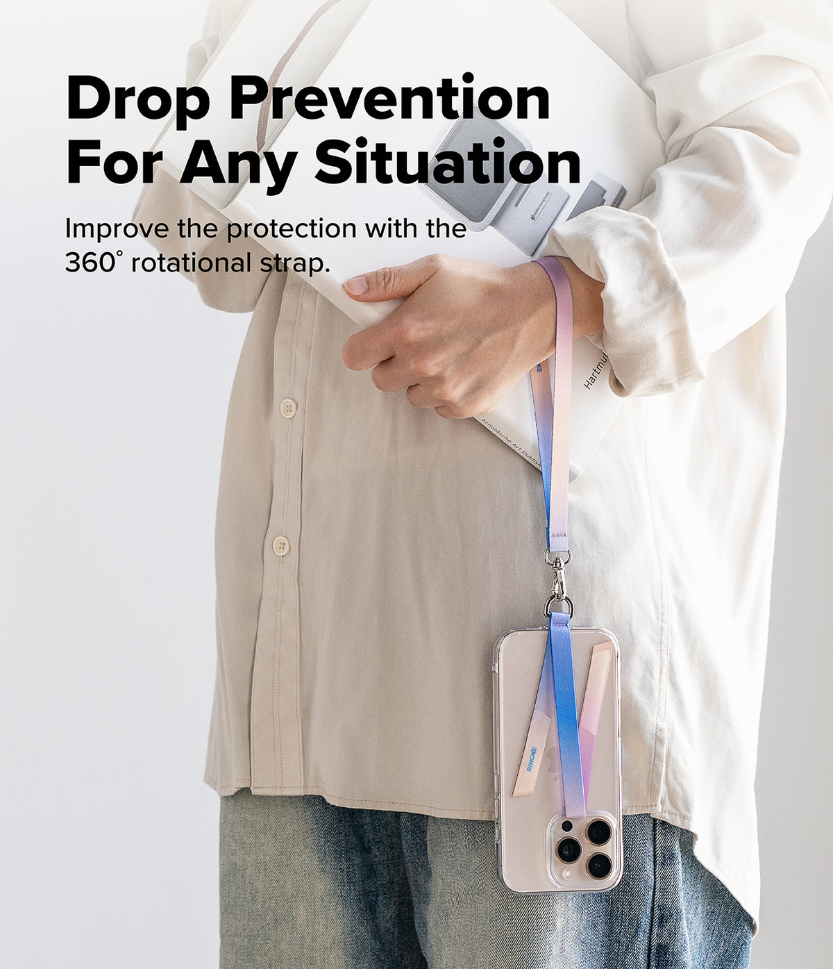 Hand Strap Hook - Person holding a book with a colorful gradient phone strap attached to a clear smartphone case.