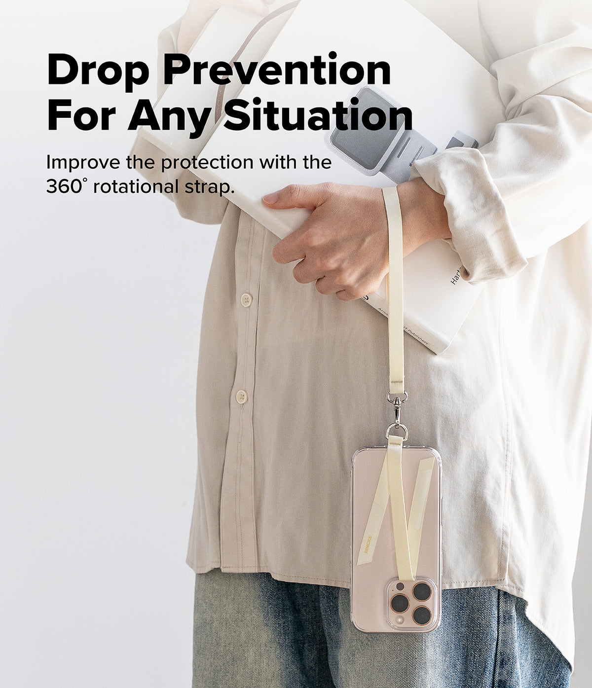 Hand Strap Hook - A person holds a book while a phone hangs from their wrist by a cream-colored 360-degree rotational strap.