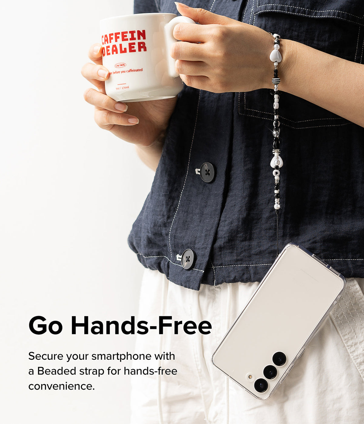 Beaded Strap - Hands holding a mug with a black and white beaded phone strap draped over the wrist attached to a phone.