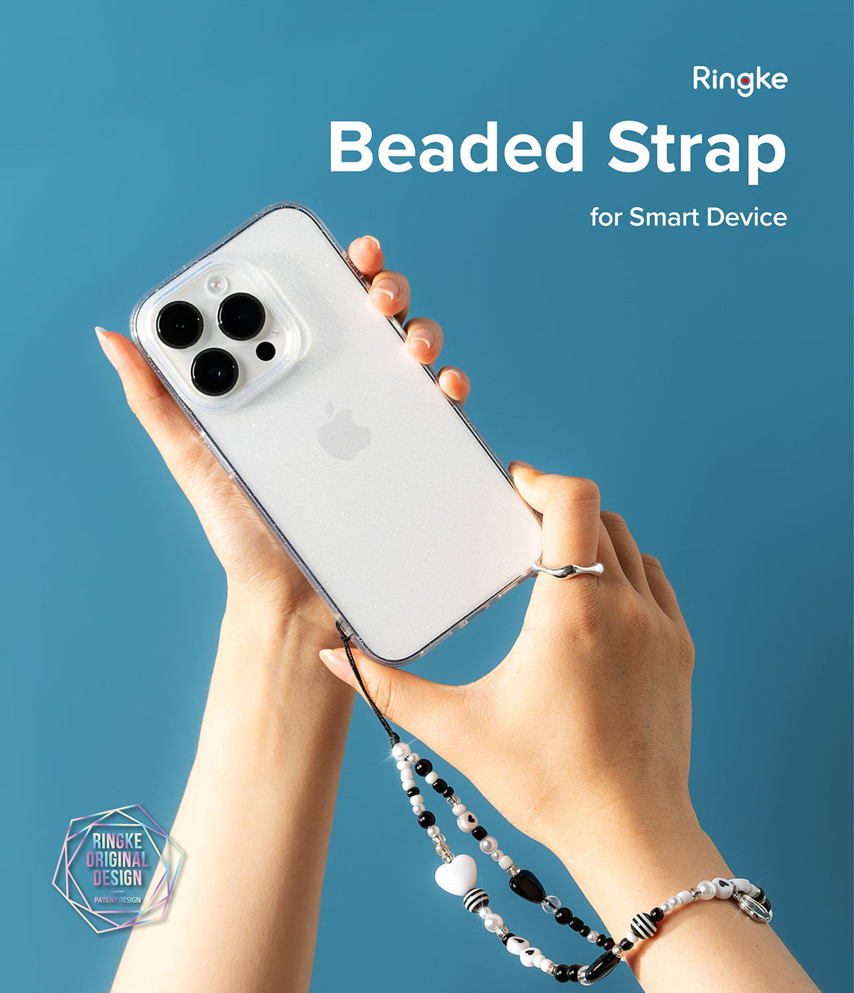 Beaded Strap - Hands holding a glittery phone case with a black and white beaded charm strap against a blue background.