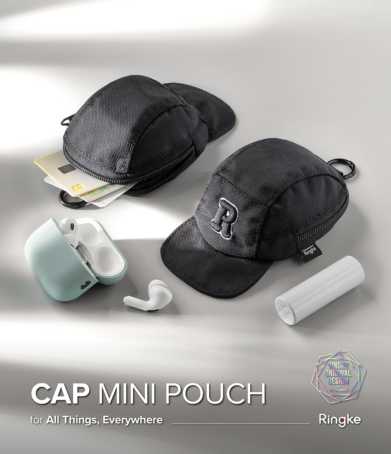 Mini Pouch | Cap - Two black cap-shaped pouches with cards, earbuds, and a small tube on a light gray surface.