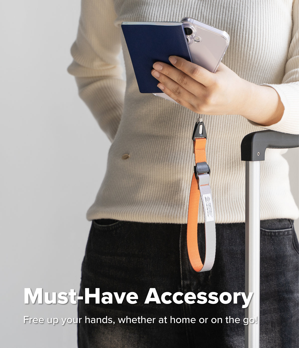 Cam Buckle Hand Strap - Person holding a phone with a lanyard, wearing a beige sweater and black pants, on a light gray background.