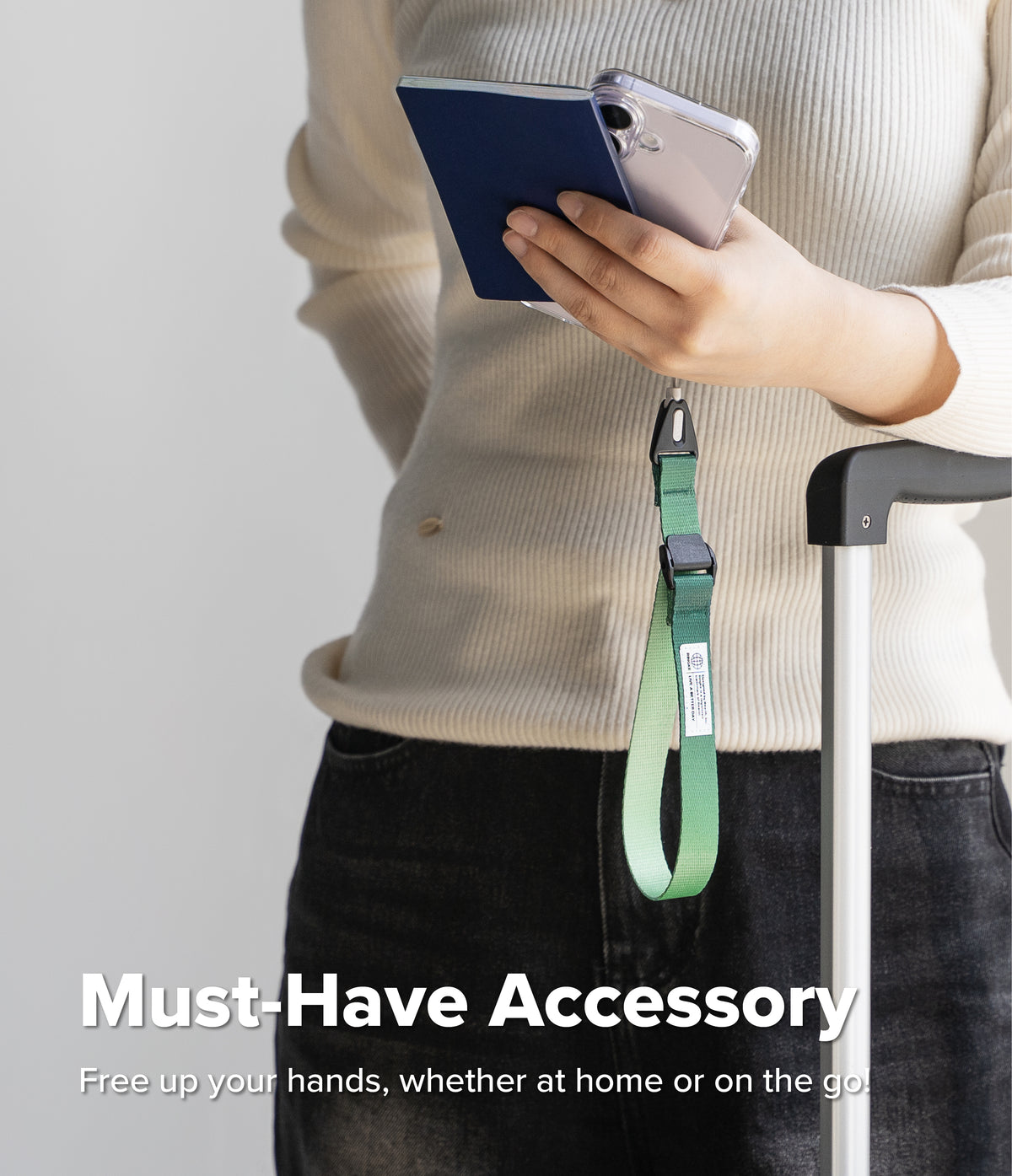 Cam Buckle Hand Strap - Person holding a phone with a green lanyard attached, standing next to a suitcase.
