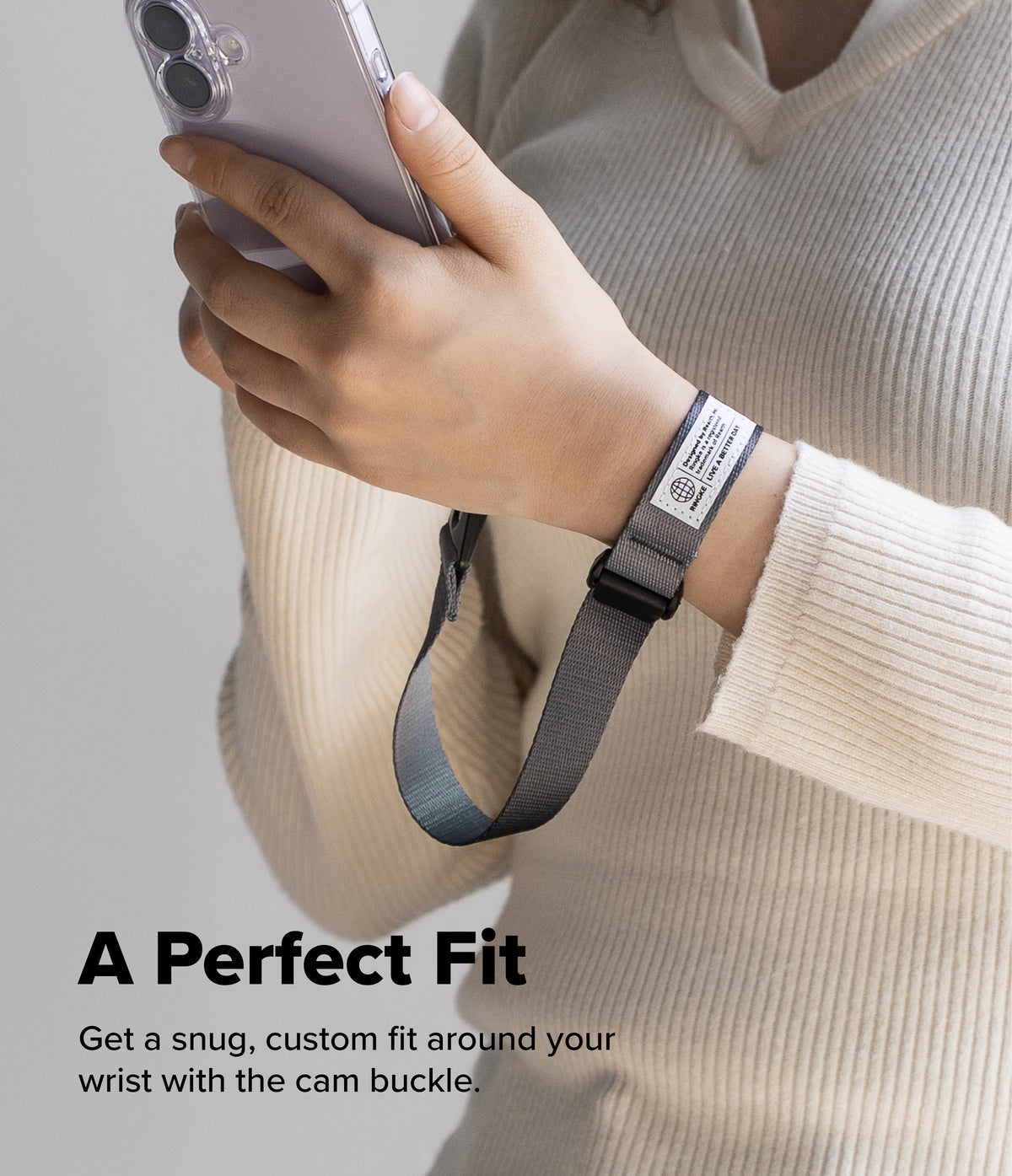 Cam Buckle Hand Strap - Hand holding a phone with a wrist strap, wearing a beige sweater on a light background.