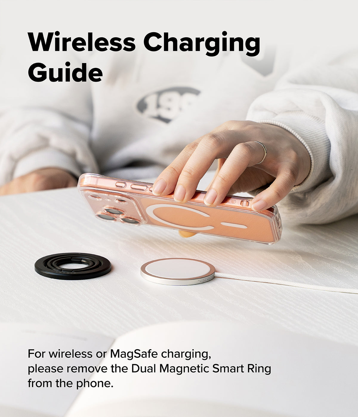Dual Magnetic Smart Ring - Hand holding a phone above a wireless charger with a detached black magnetic ring on the table.