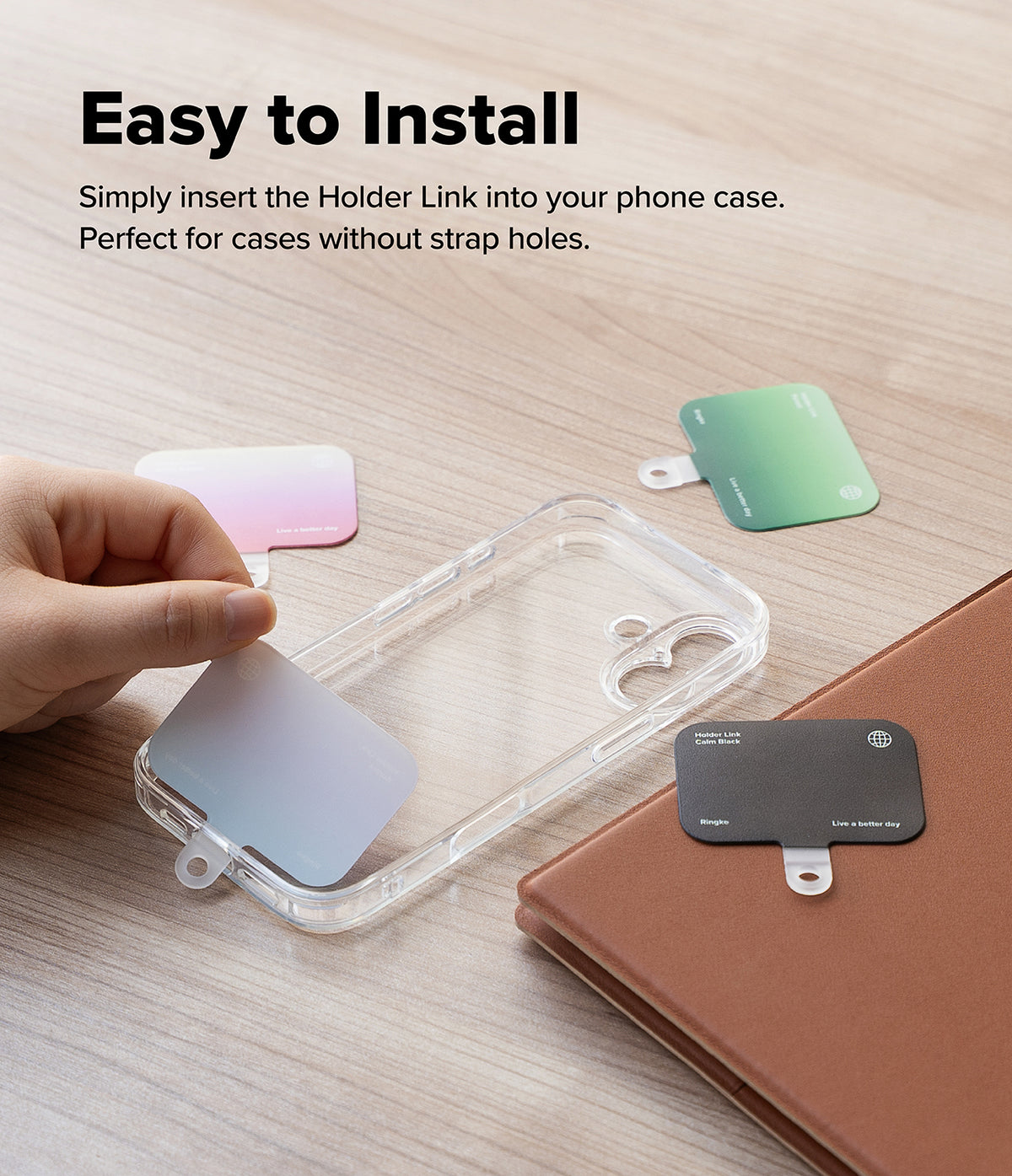 Holder Link Eyelet Keyring - Hand placing a thin, colorful strap anchor into a clear phone case on a wooden surface.