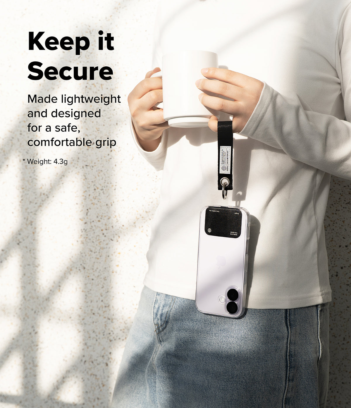 Holder Link Eyelet Keyring - A person holds a mug while a smartphone hangs from their wrist by a black fabric strap.