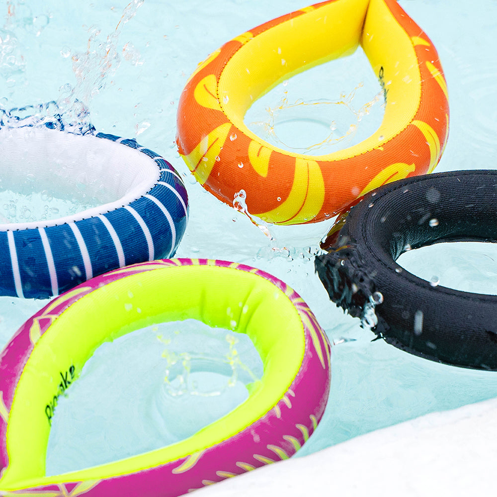4 colorful straps float on water, with splashes around them. The straps are yellow, orange, black, blue-striped, and pink with green.