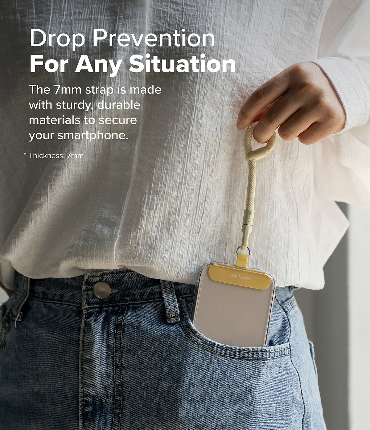 Holder Link Flow Finger Ring - A hand holds a beige finger strap attached to a smartphone case tucked into jeans.