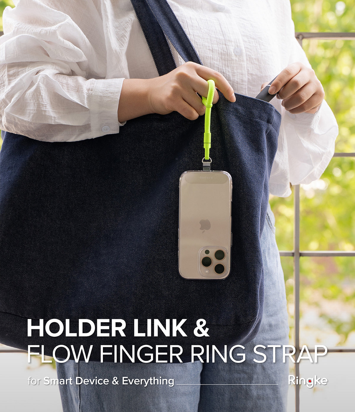Holder Link Flow Finger Ring - A neon yellow finger strap attached to a smartphone hanging from a dark blue tote bag.