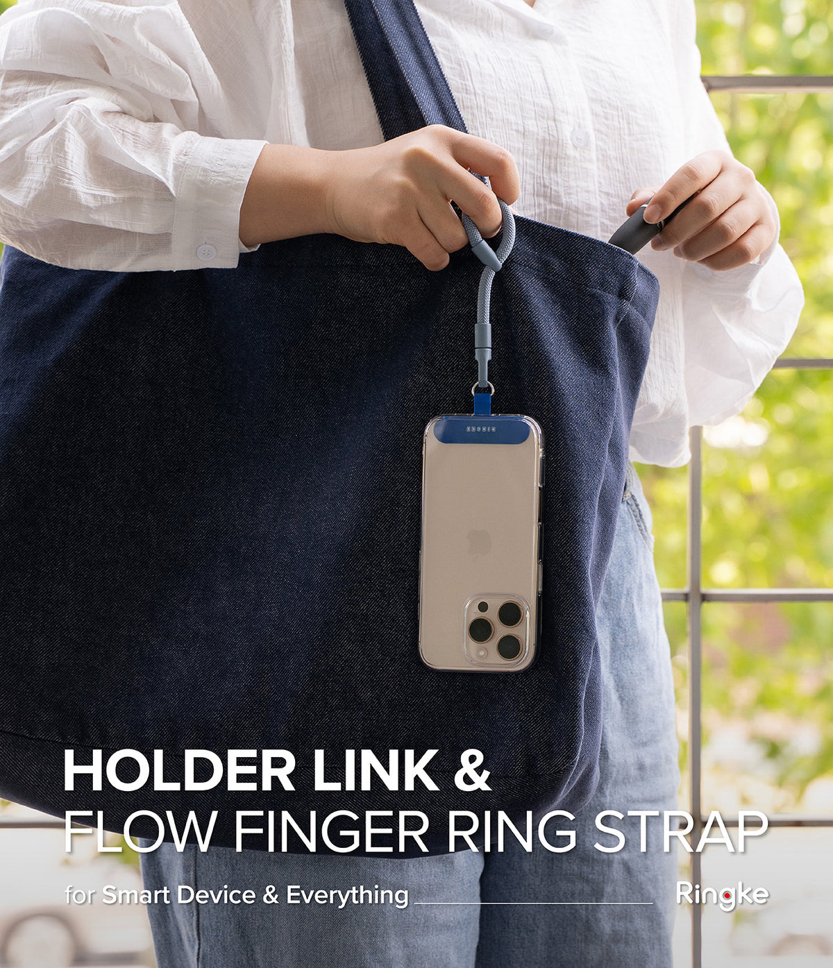 Holder Link Flow Finger Ring - A person holding a blue finger ring strap attached to a smartphone hanging from a denim tote bag.