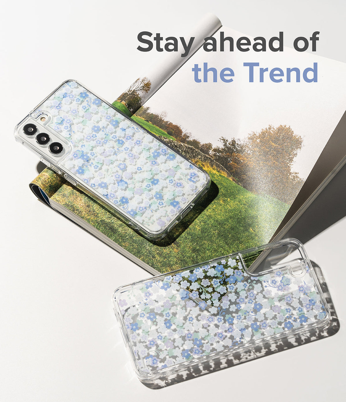 Galaxy S22 Plus Case | Fusion Design - Two clear phone cases with blue floral patterns resting on an open magazine.