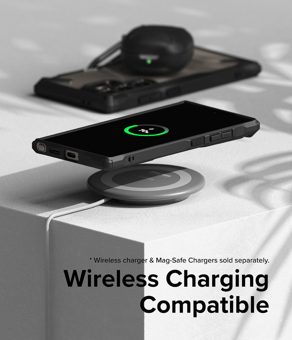 Galaxy S24 Ultra Case | Fusion-X - Galaxy S24 Ultra in a black case wirelessly charging on a pad with earbuds in the background.