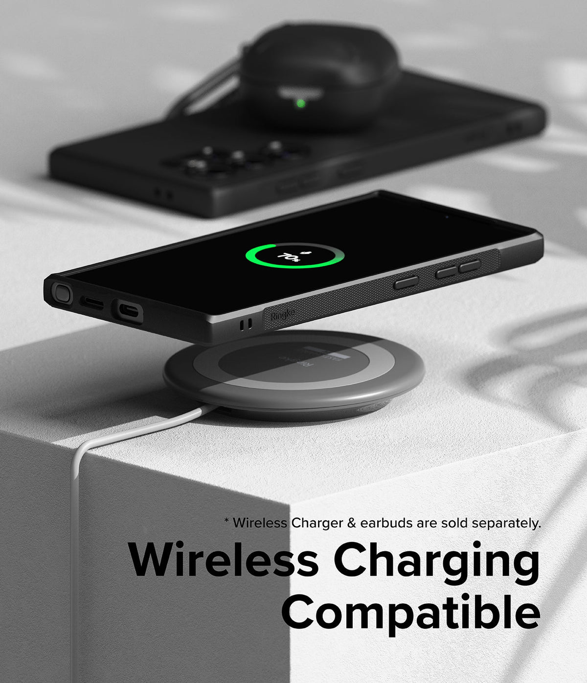 Galaxy S24 Ultra Case | Onyx - Black phone in case wirelessly charging on a circular pad with earbuds in the background.