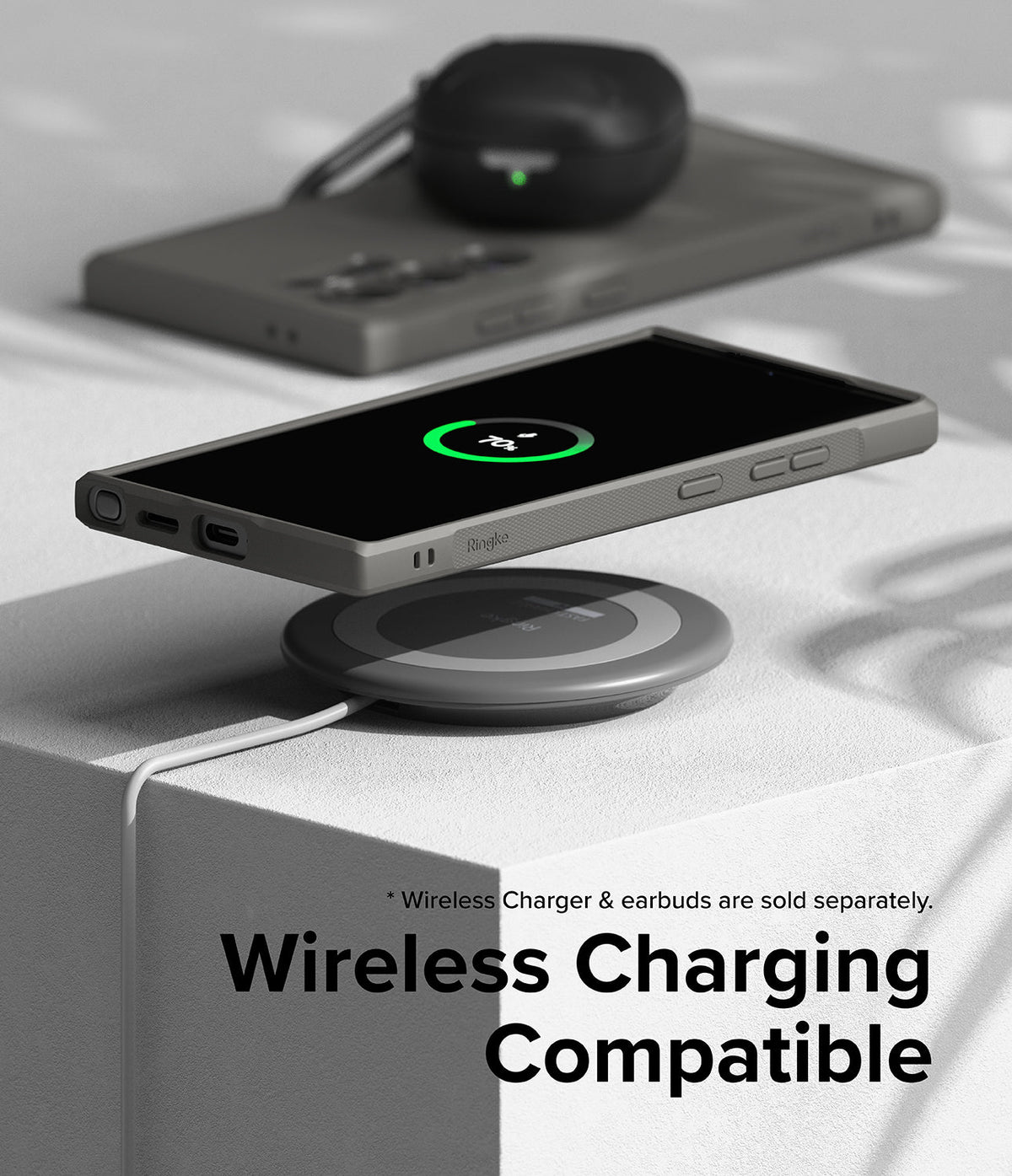 Galaxy S24 Ultra Case | Onyx - Smartphone in an onyx case wirelessly charging on a pad with earbuds in the background.
