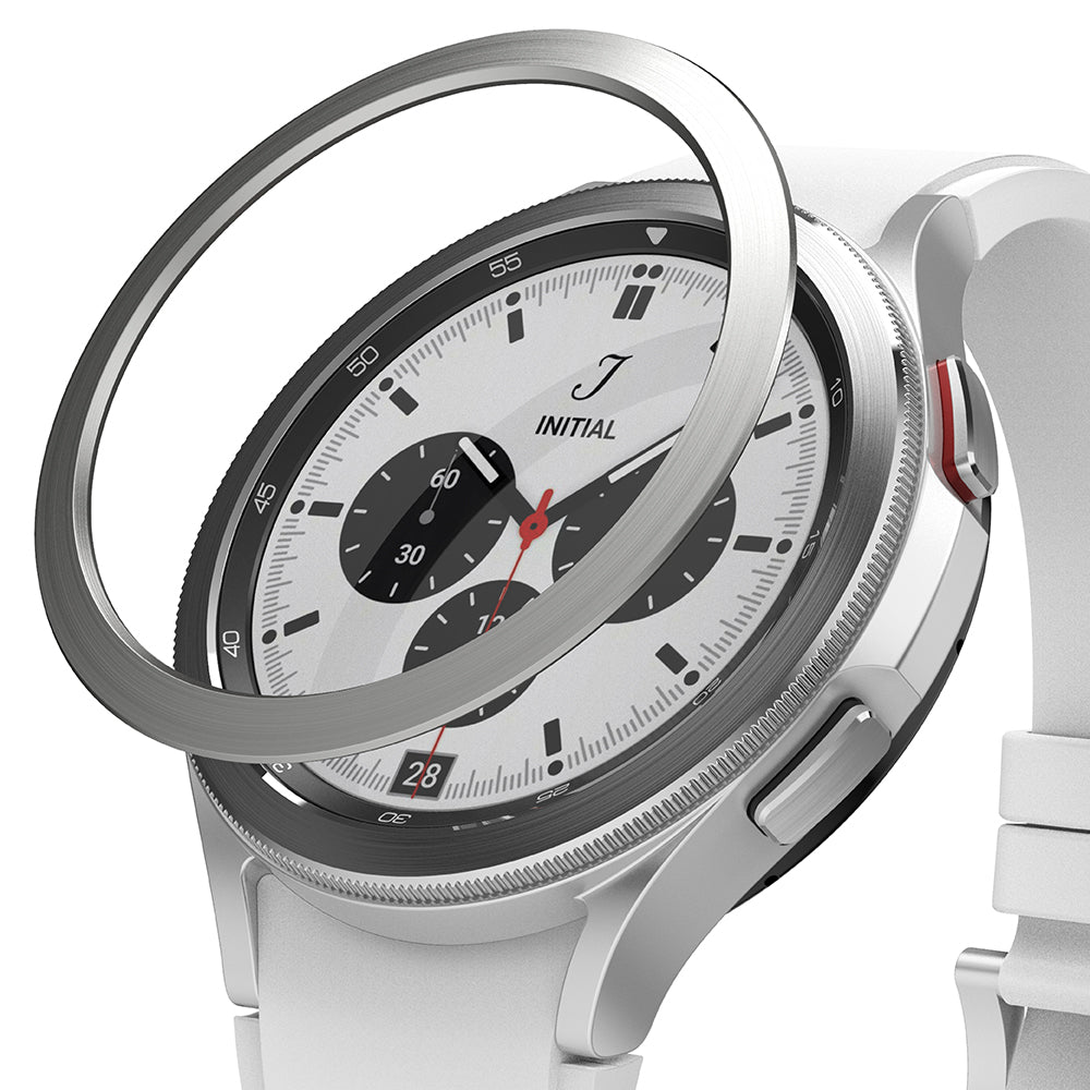 Galaxy Watch 4 Classic 46mm | Bezel Styling - Galaxy Watch 4 Classic 46mm - A silver metal bezel ring hovering above a white smartwatch with a chronograph watch face.