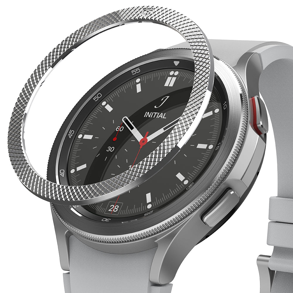 Galaxy Watch 4 Classic 46mm | Bezel Styling - Galaxy Watch 4 Classic 46mm | A silver textured bezel ring hovering above a silver smartwatch with a black watch face.