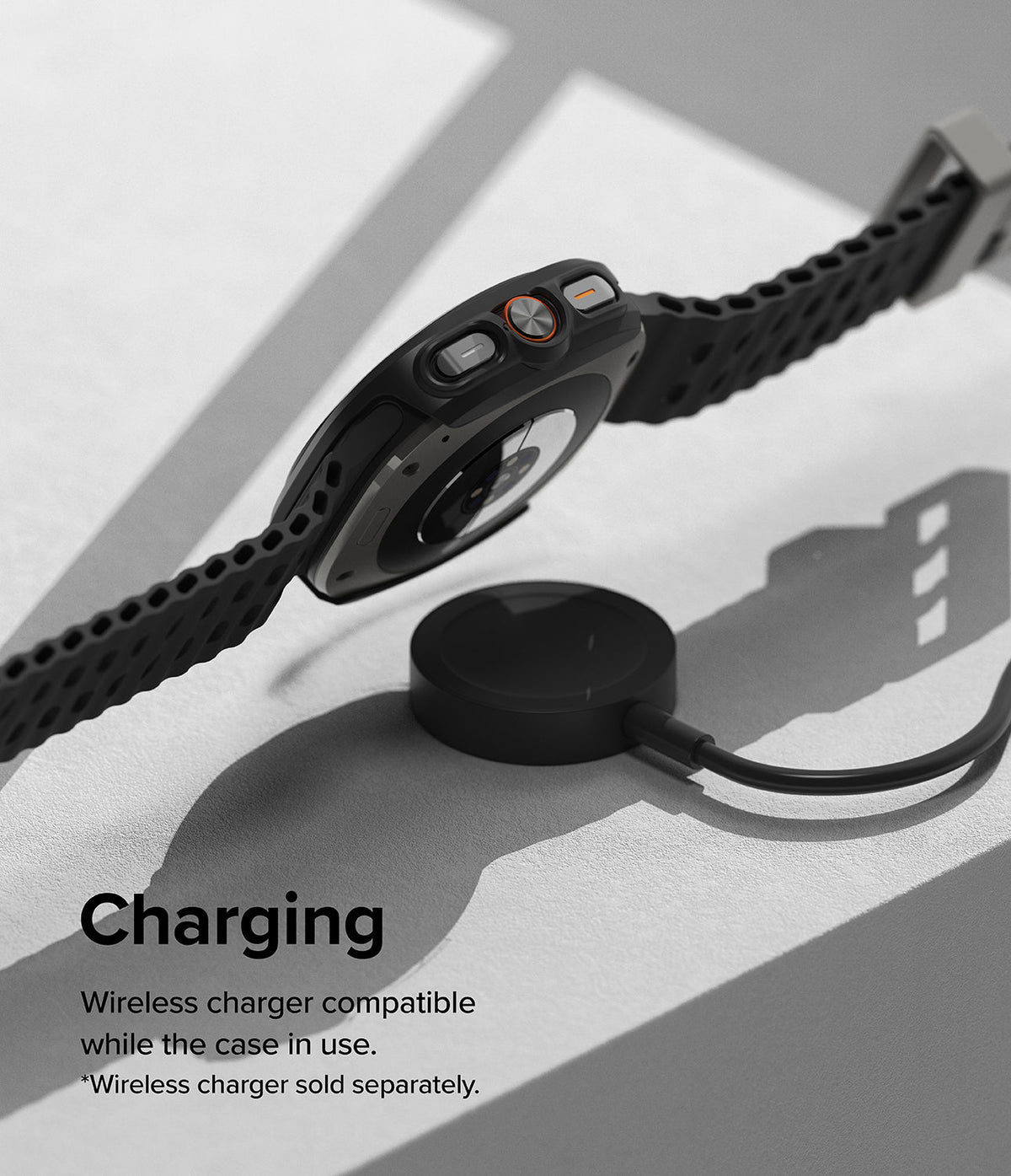 Galaxy Watch Ultra | Slim & Glass - A black smartwatch in a protective case hovering above a wireless charging puck.