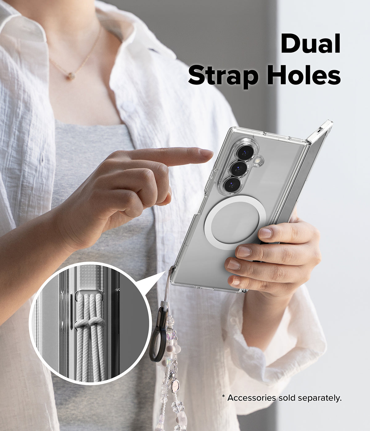 Galaxy Z Fold 8 Ultra Case | Fusion Magnetic - A person holding a silver smartphone in a clear case, with text reading 'Dual Strap Holes' and a circular inset showing a rope strap attached through the double strap holes. The person wears a white shirt over a gray top against a light gray background.