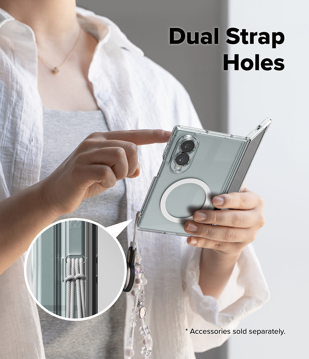Galaxy Z Fold 8 | Fusion Magnetic - A person holds a silver foldable smartphone in a clear protective case with a circular MagSafe ring and a dangling cord. The image includes the text 'Dual Strap Holes' and a circular inset showing the cord threaded through the strap holes of the case.