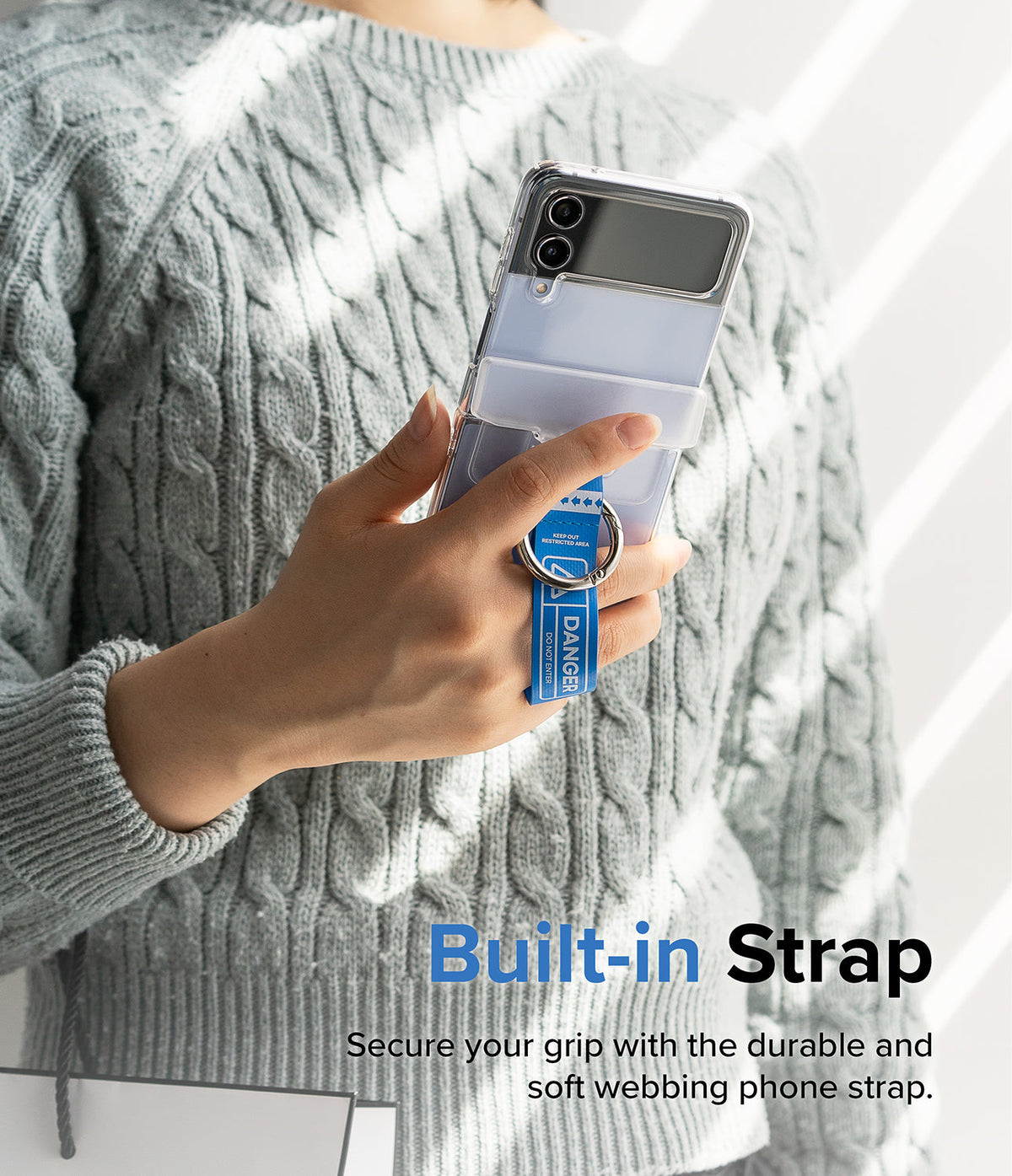 Galaxy Z Flip 7 FE / 6 / 5 / 4 / 3 | Hinge Cover Tarpaulin - Hand holding a foldable phone with a blue danger-themed strap.