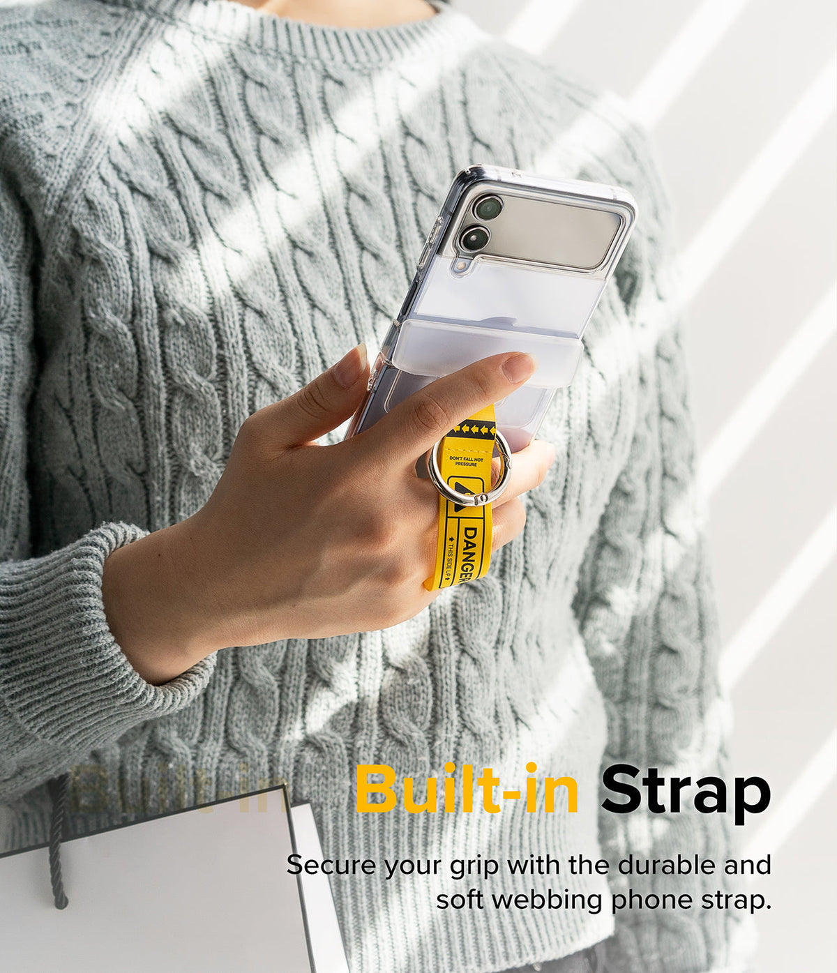 Galaxy Z Flip 7 FE / 6 / 5 / 4 / 3 | Hinge Cover Tarpaulin - Galaxy Z Flip 7 FE / 6 / 5 / 4 / 3 | Person holding a phone with a yellow "DANGER" warning strap and metal ring.