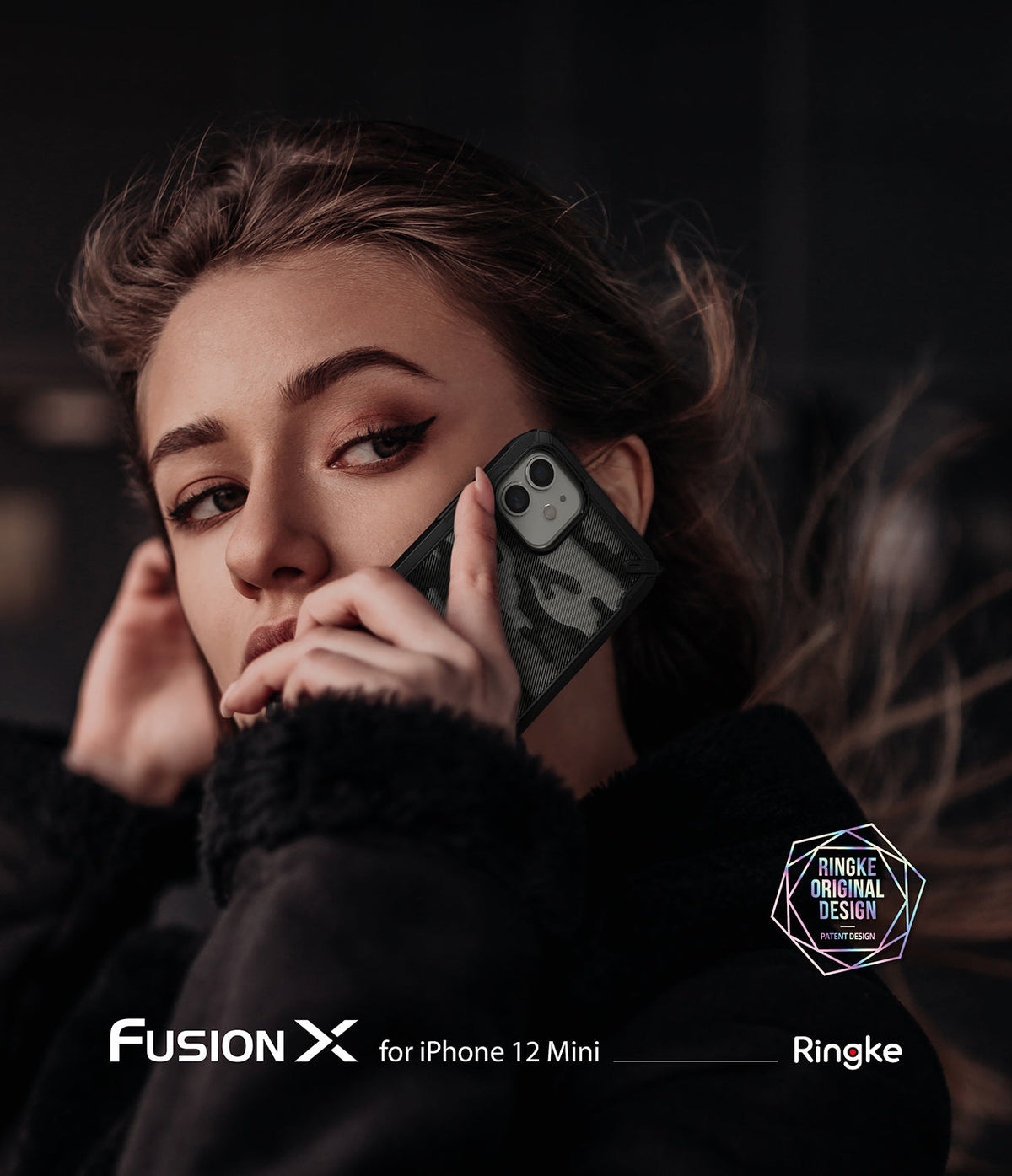 iPhone 12 Mini Case | Fusion-X - A woman holding a camo-patterned Fusion-X phone case against her ear in a dark setting.