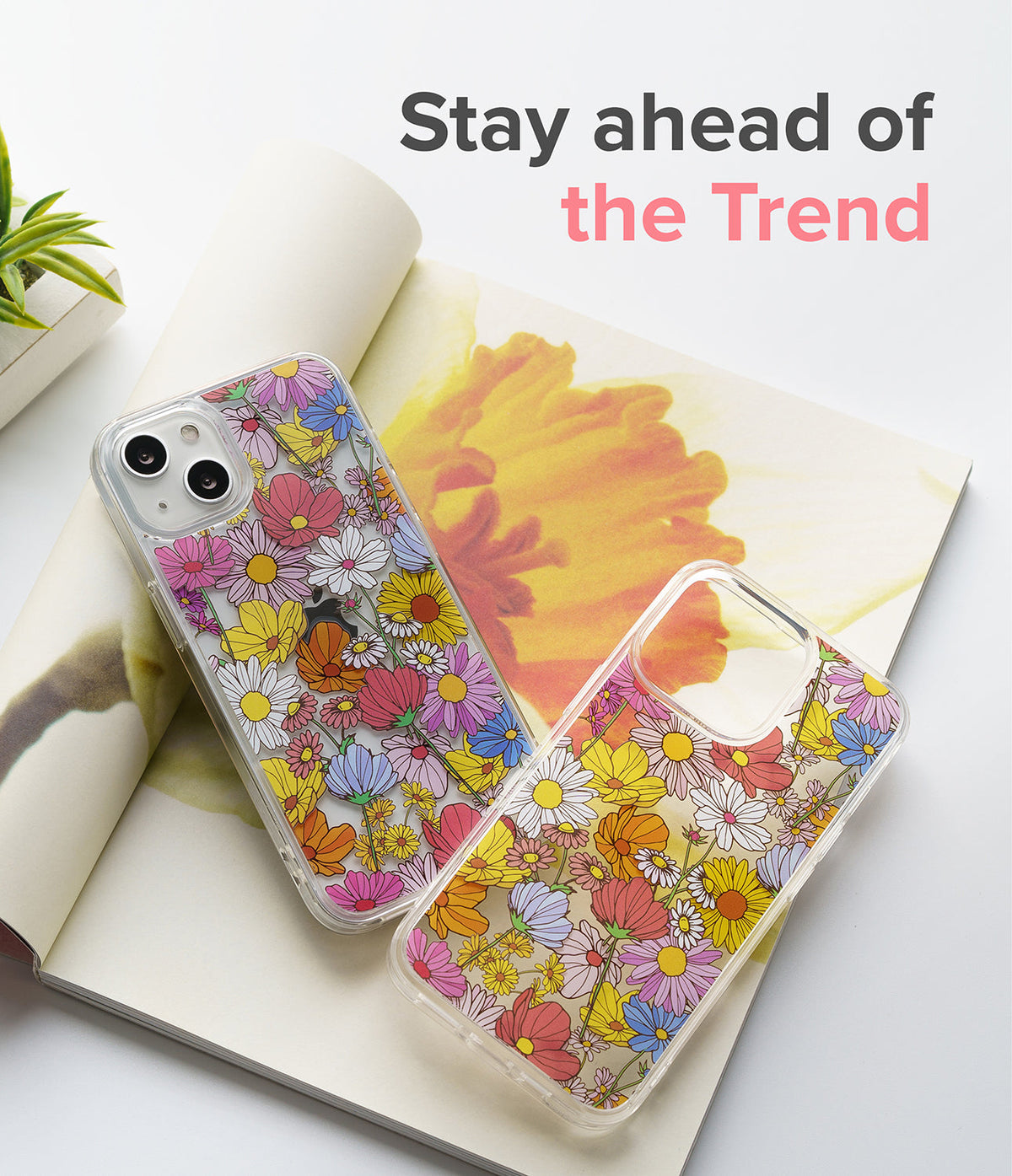 iPhone 13 Case | Fusion Design - Two clear phone cases with colorful floral patterns resting on an open magazine.