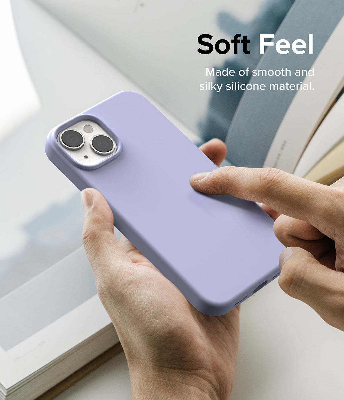 iPhone 14 Plus Case | Silicone - A hand touches a smooth, light purple silicone iPhone 14 Plus case with text Soft Feel.