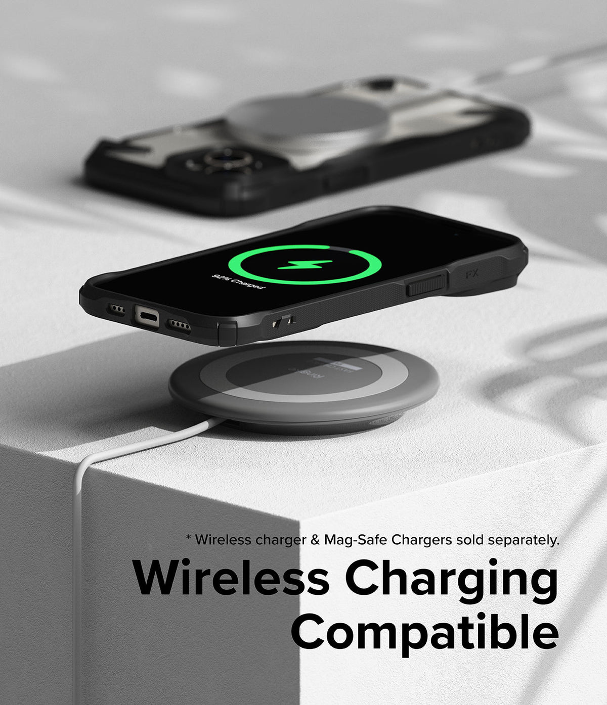 iPhone 15 Plus Case | Fusion-X - iPhone 15 Plus in a black Fusion-X case wirelessly charging on a pad with a green charging icon.