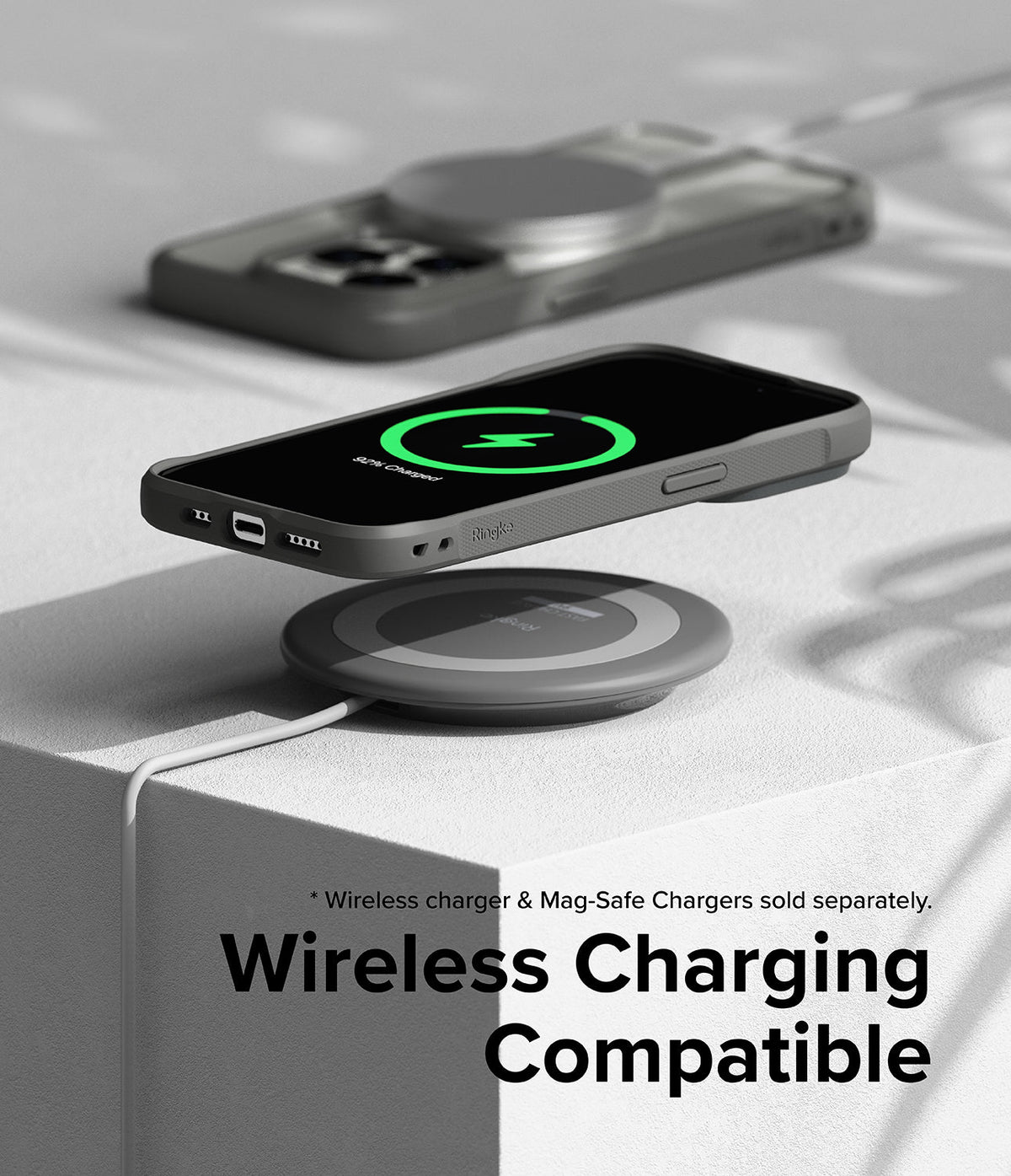 iPhone 15 Pro Case | Fusion Bold - Grey phone case hovering over a wireless charging pad showing a green charging icon.