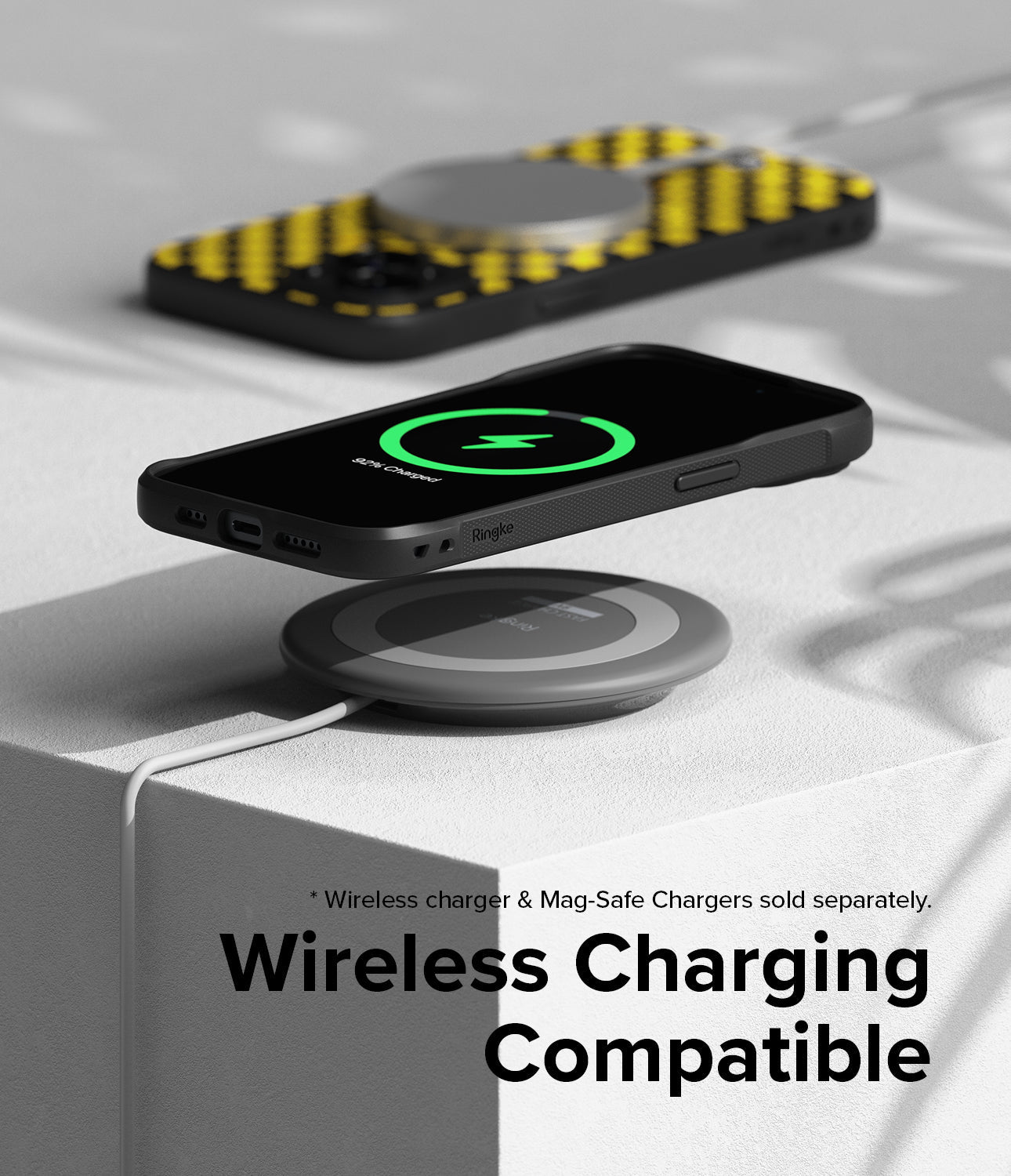 iPhone 15 Plus Case | Onyx Design - Black phone case with yellow pattern charging wirelessly on a grey pad.